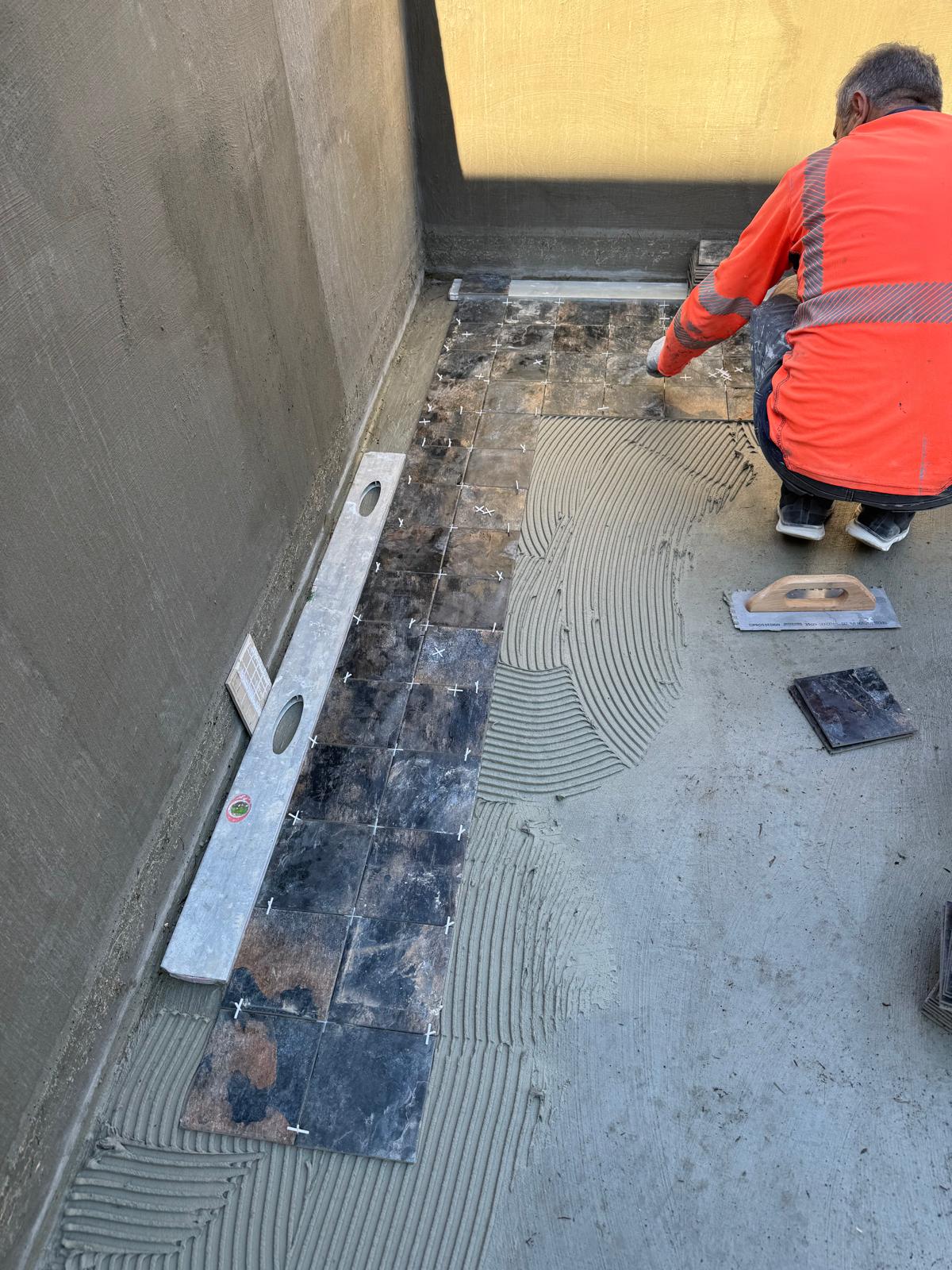 Artisan 3DC posant le carrelage piscine avec niveau